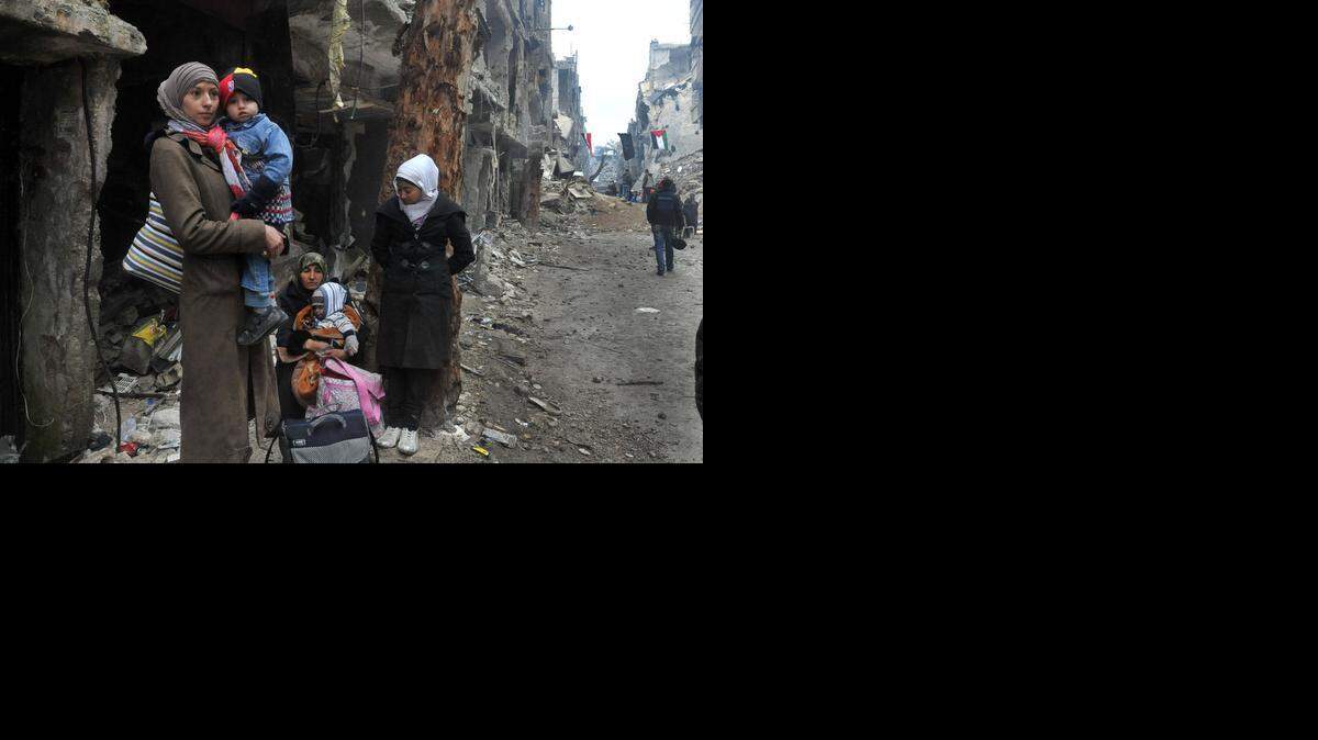 
Una familia de refugiados espera entre las ruinas del campo de Al Yarmuk, que se encuentra en medio de una guerra civil entre muchas facciones.
