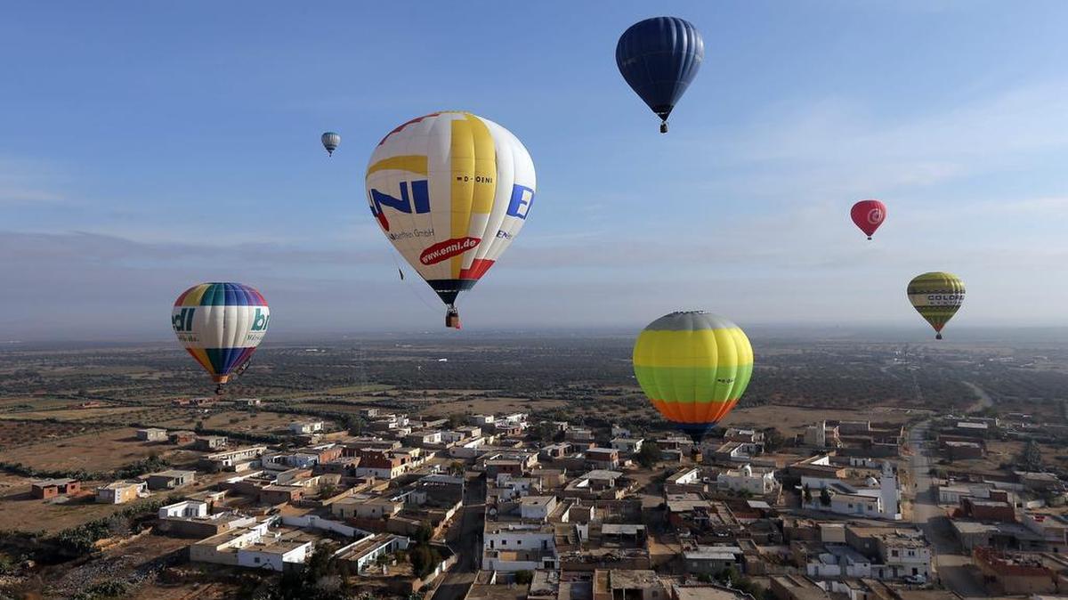 Globos de aire caliente flotan por encima de los campos y las casas durante el festival del globo de Túnez en Sousse, al sur de Túnez, Túnez, el 19 de marzo de 2016.