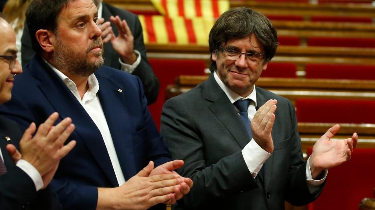 El presidente del Ejecutivo catalán, Carles Puigdemont (der.), aplaude junto al vicepresidente Oriol Junqueras, luego de una votación durante una sesión del Parlamento catalán el 6 de septiembre.