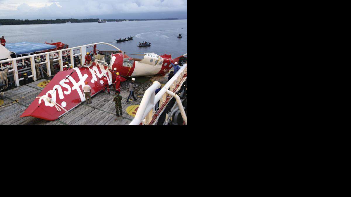 
Miembros del equipo de Crest Onyx se preparan para levantar la cola del avión de AirAsia rescatada del mar de Java.


