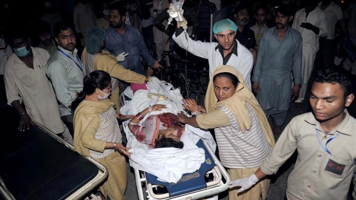 Familiares y personal de emergencia trasladan a un hospital a una mujer herida tras el ataque en Lahore, Pakistán.