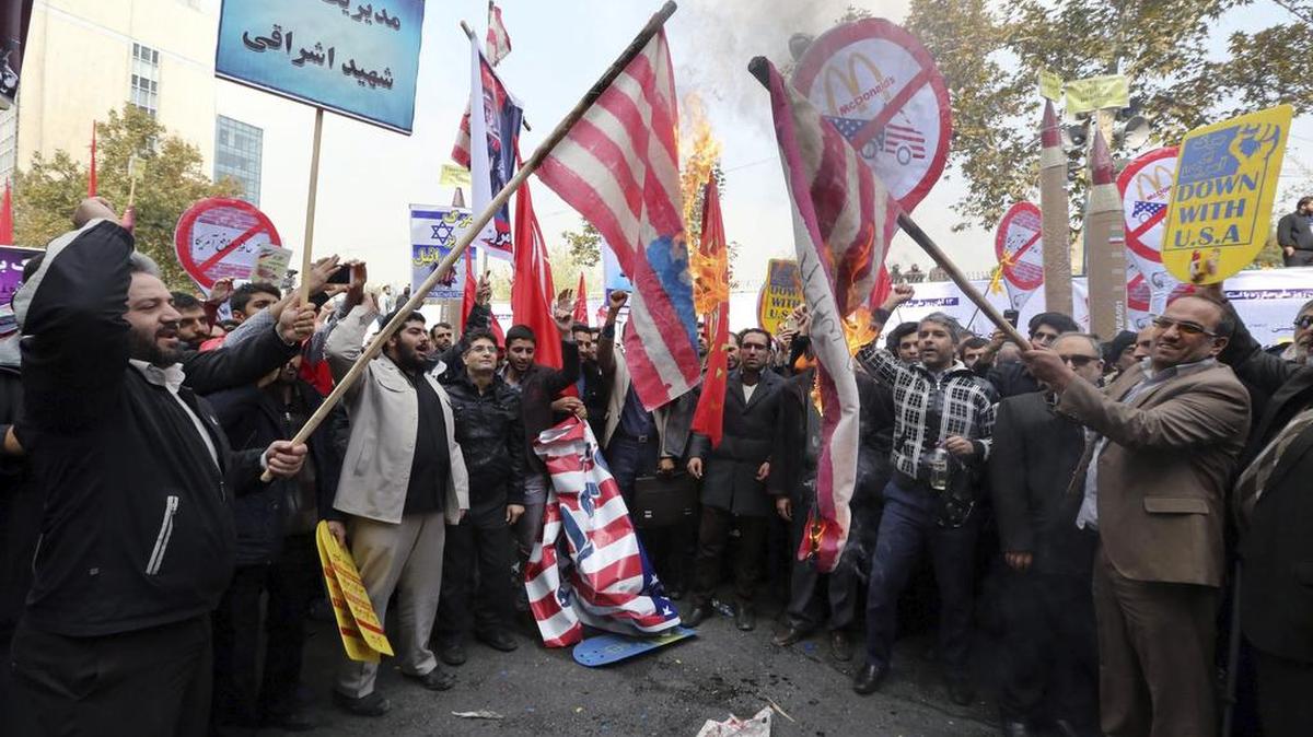 Manifestantes iraníes queman banderas durante una protesta con motivo del 36 aniversario de la toma de la embajada estadounidense en la capital iraní en el 1979 en Teherán, Irán,