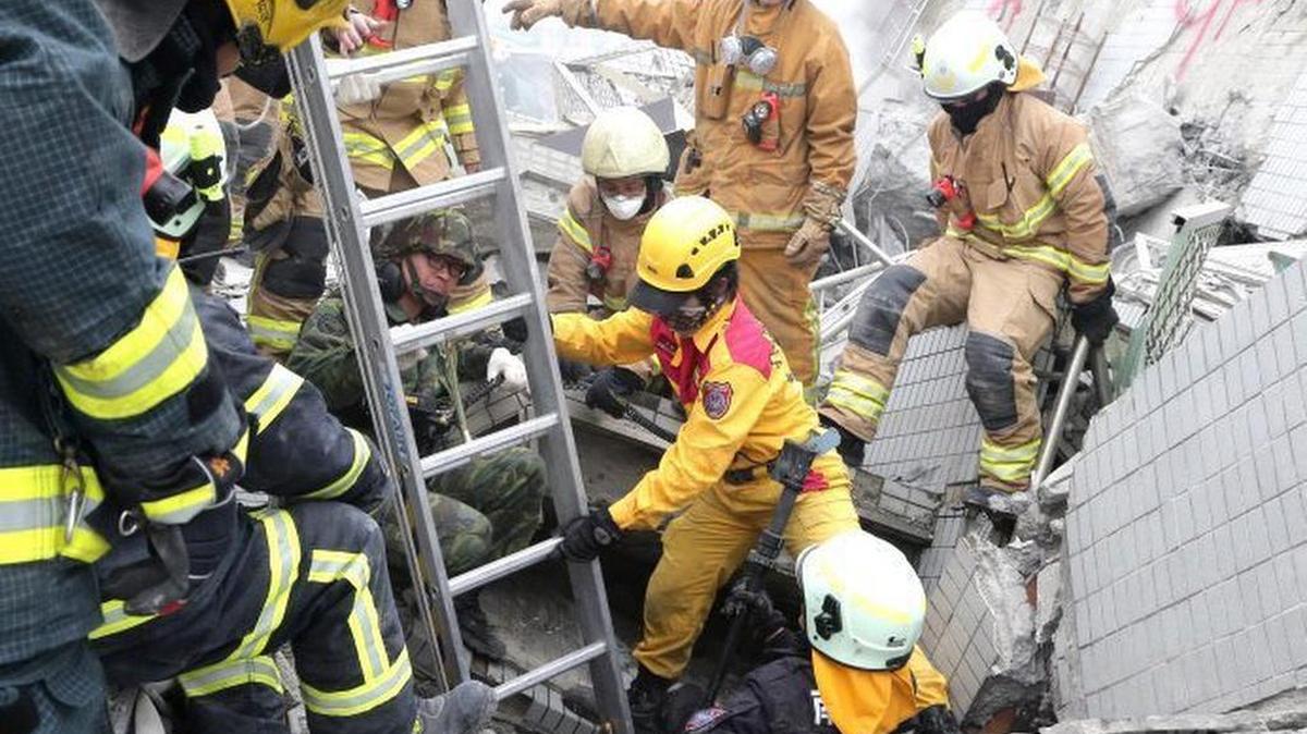 Varios miembros de los servicios de rescate mientras buscan víctimas entre los escombros de un edificio derrumbado en la ciudad de Tainan (Taiwán) este 11 de febrero de 2016.