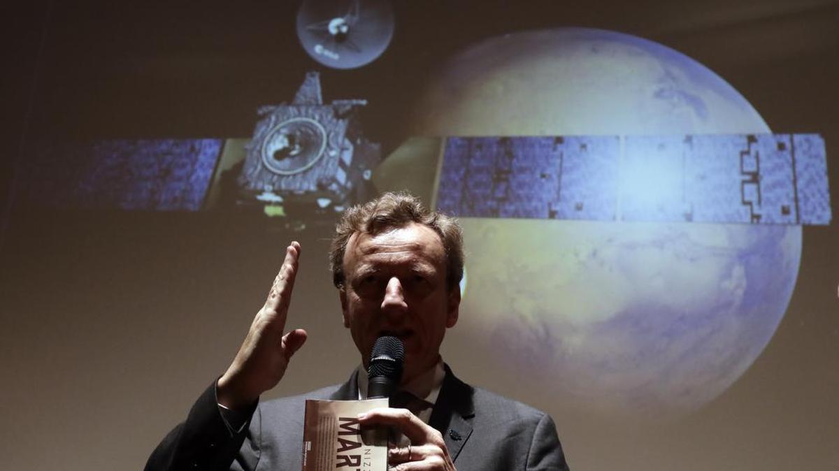 El presidente de la Agencia Espacial Italiana, Roberto Battiston habla a la prensa frente a una ilustración del descenso de Schiaparelli en el Planeta Rojo.