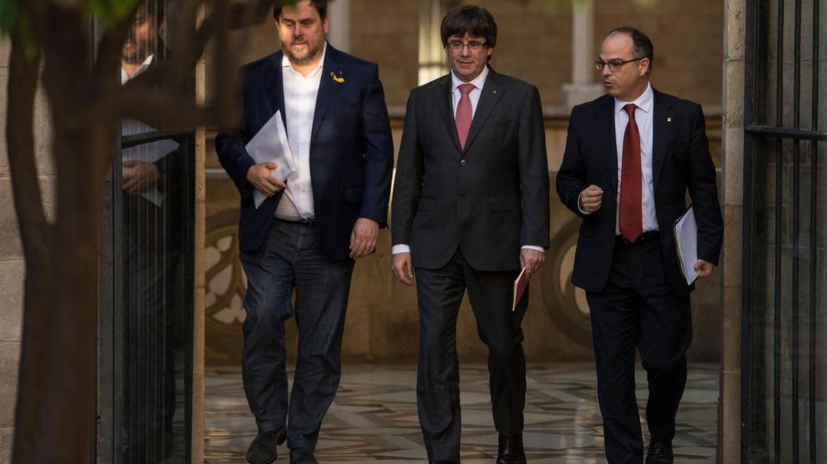 El presidente del Gobierno regional catalán Carles Puigdemont (C) llega con el vicepresidente regional y jefe de Economía y Finanzas de Cataluña Oriol Junqueras (L) y el vocero del Gobierno catalán Jordi Turull para asistir a una reunión del gobierno regional en el Palacio de la Generalitat en Barcelona el 24 de octubre de 2017.