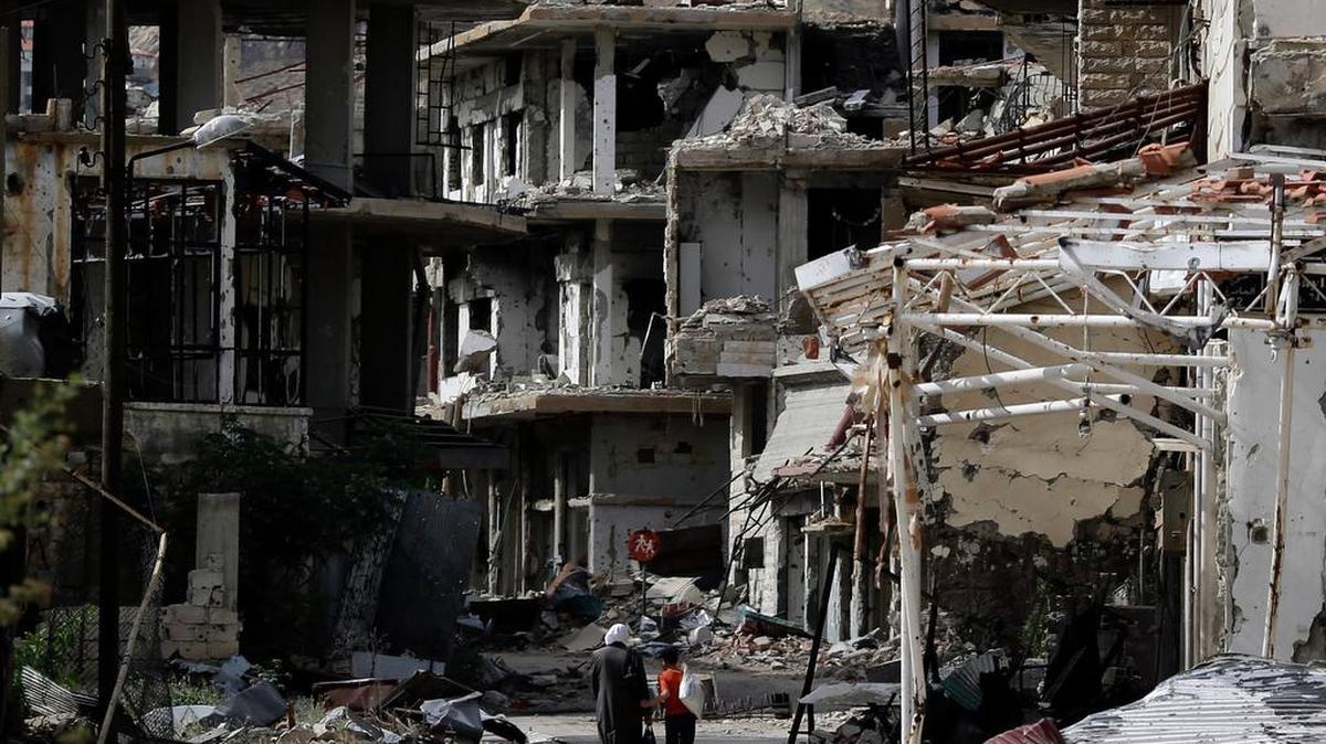 Residentes caminan entre edificios destruidos por la aviación del gobierno de Bashar al-Assad, en Damasco, Siria, el 18 de mayo del 2017.