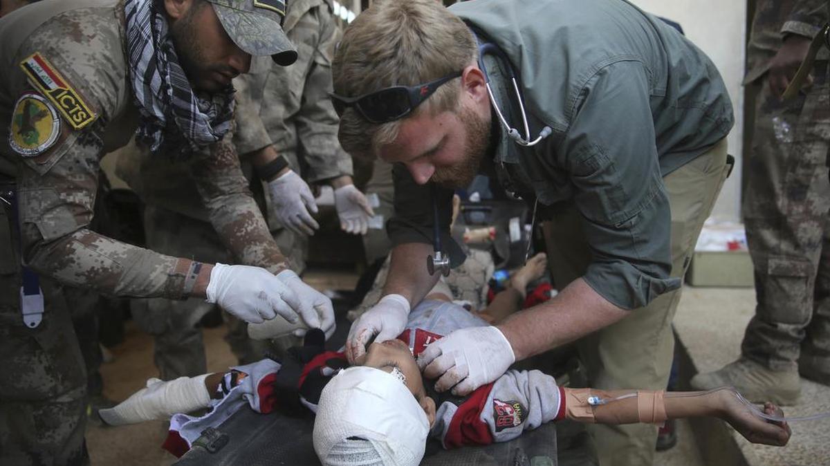 Un médico voluntario estadounidense y un soldado iraquí asisten a un niño herido en los combates por Mosul.