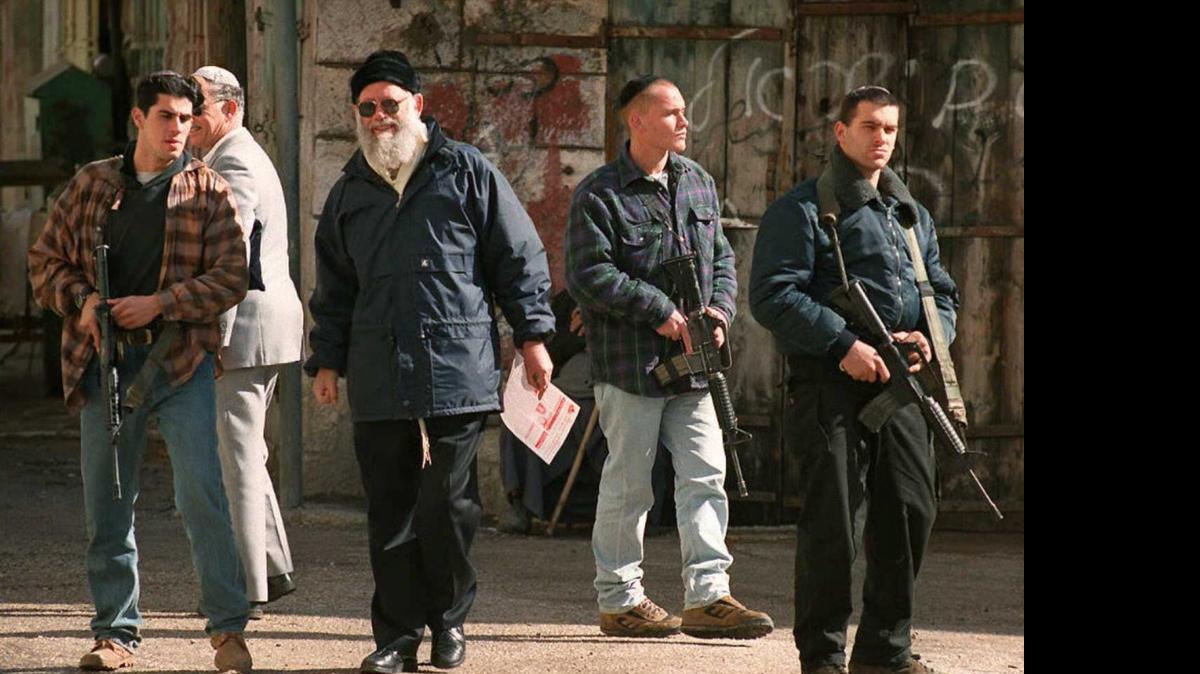 
El rabino Moshé Levinger (cent.), fundador del movimiento que inició los asentamientos de colonos judíos en Cisjordania, protegido por sus guardaespaldas, en enero de 1996.
