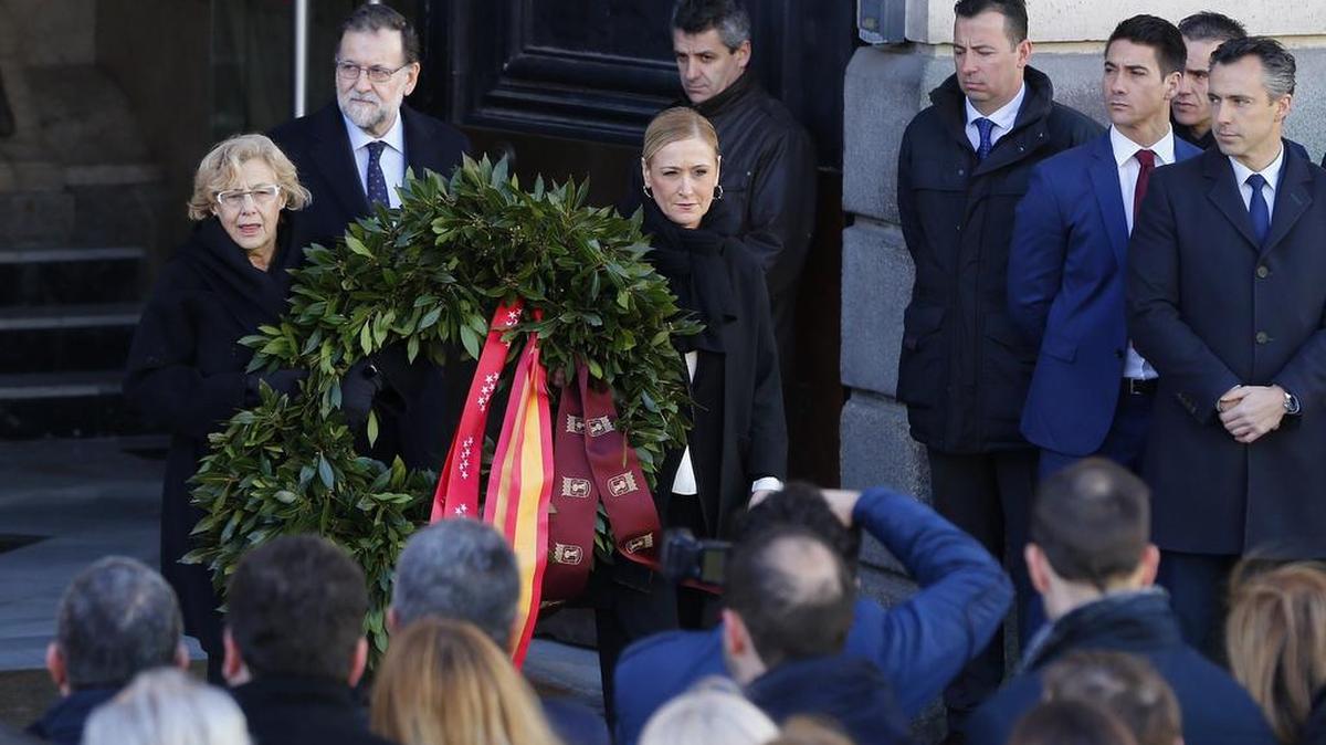 El jefe del Ejecutivo en funciones, Mariano Rajoy (izq.), junto a la presidenta de la Comunidad de Madrid, Cristina Cifuentes (der.), y la alcaldesa de la capital, quienes colocaron una corona de flores en la Puerta del Sol durante el homenaje.