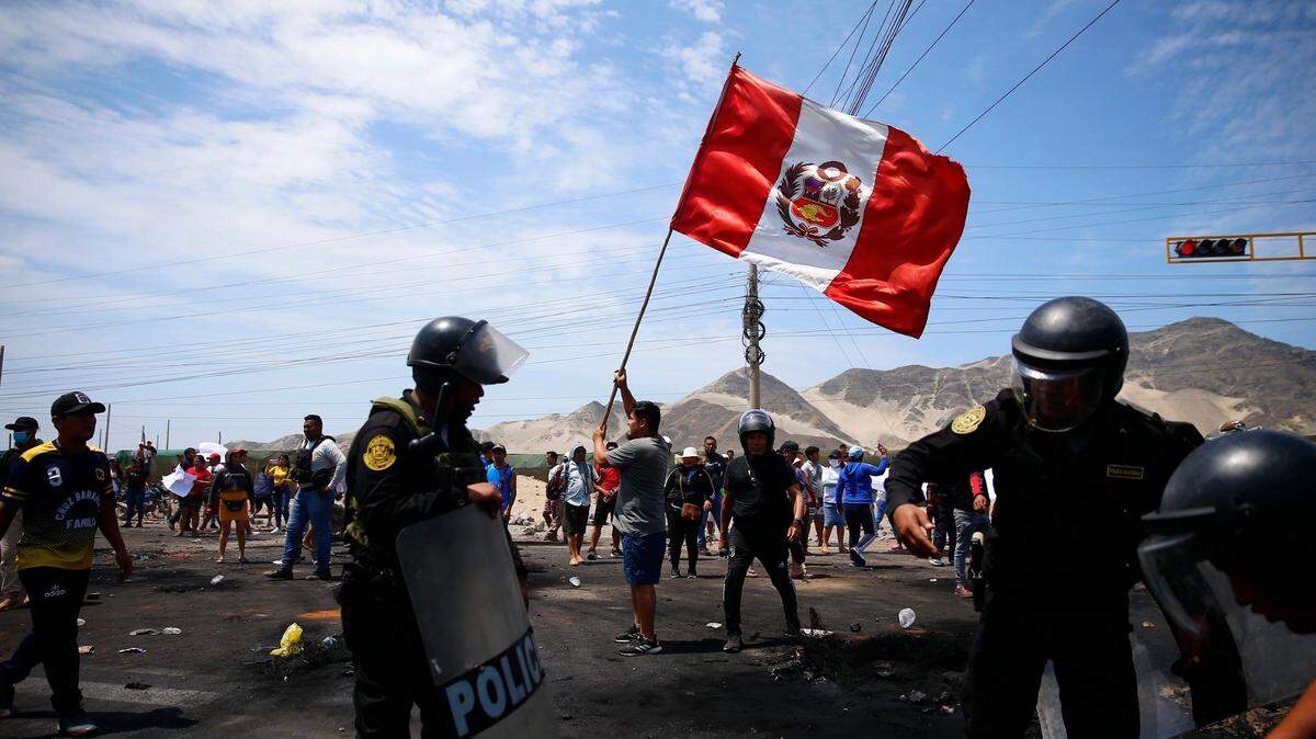 Partidarios del destituido presidente peruano Pedro Castillo protestan en la Carretera Panamericana Norte mientras los policías llegan para limpiar los escombros, en Chao, Perú, el jueves 15 de diciembre de 2022. (AP foto/Hugo Curotto)