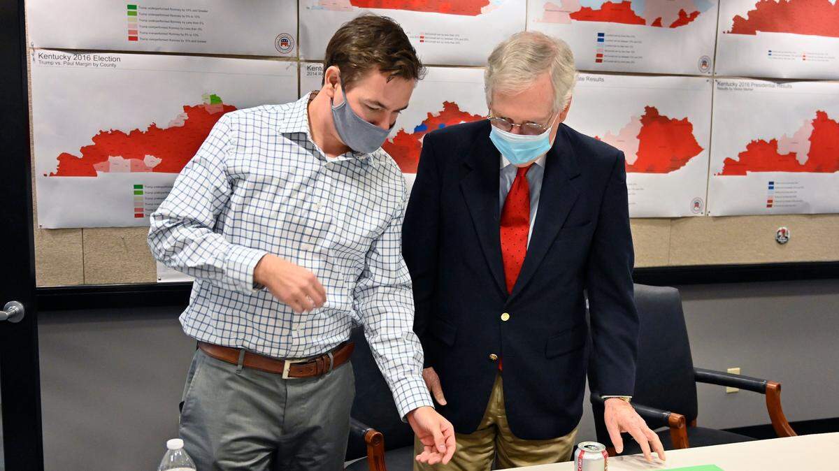El senador republicano Mitch McConnell (der.) mira los resultados de la elección con un miembro de su equipo de campaña, el martes en Louisville, Kentucky. El líder del Senado fue reelecto tras derrotar a la ex piloto Amy McGrath.