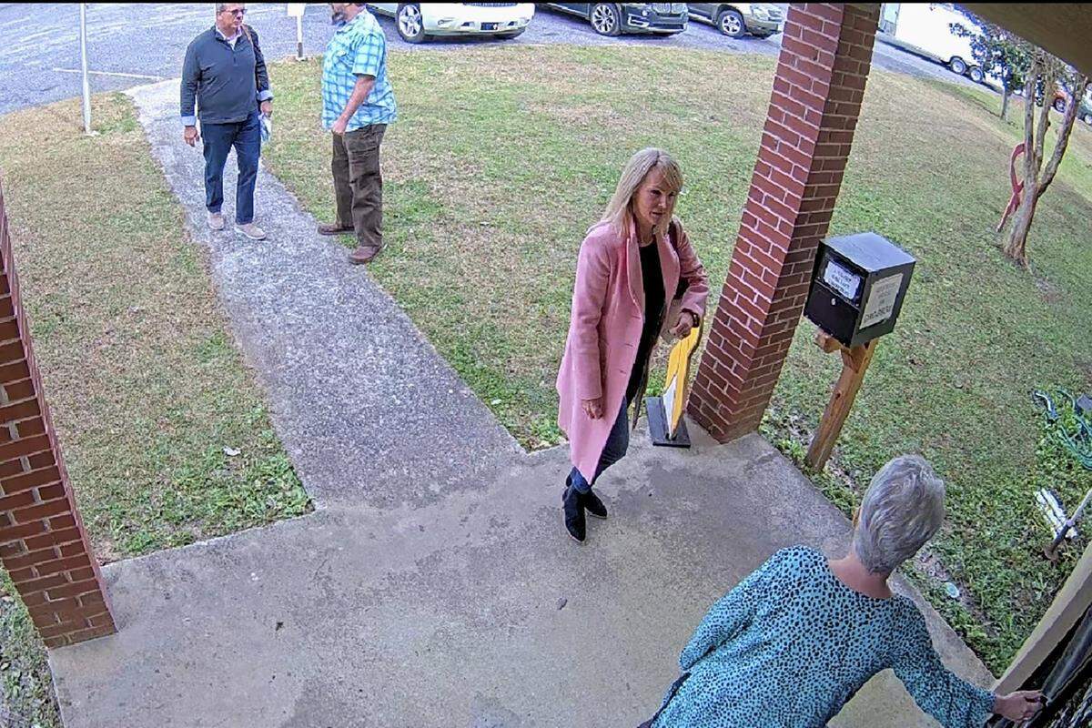 In this Jan. 19, 2021 photo taken from Coffee County, Ga. security video, Cathy Latham, bottom, who was the chair of the Coffee County Republican Party at the time, greets a team of computer experts from the SullivanStrickler data solutions at the county elections office in Douglas, Georgia. Records show the team traveled to the rural South Georgia county to copy election equipment software and data. The Georgia secretary of state’s office has said the visit was an “alleged unauthorized access” to election equipment. (Coffee County via AP)