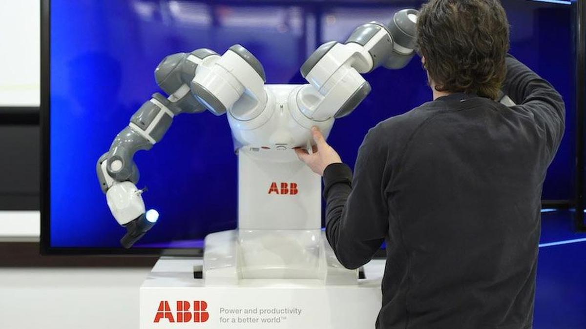 Trabajadores preparan un robot de doble brazo YuMi en el stand de ABB de Suiza en la feria industrial de Hannover Messe en Hannover, Alemania central, 2015.