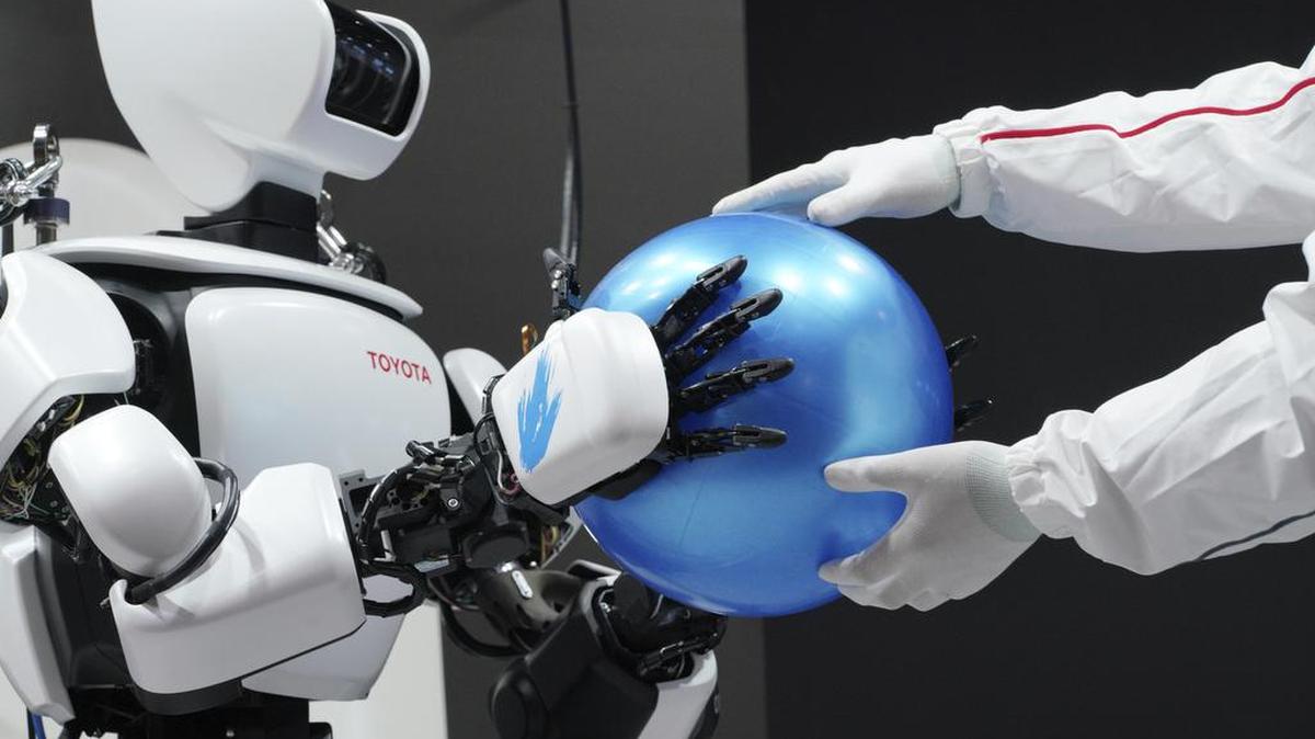 El robot humanoide T-HR3 de tercera generación de Toyota, controlado de forma remota por un miembro del personal, sostiene una pelota en la Exposición Internacional de Robots en Tokio el miércoles 29 de noviembre de 2017.