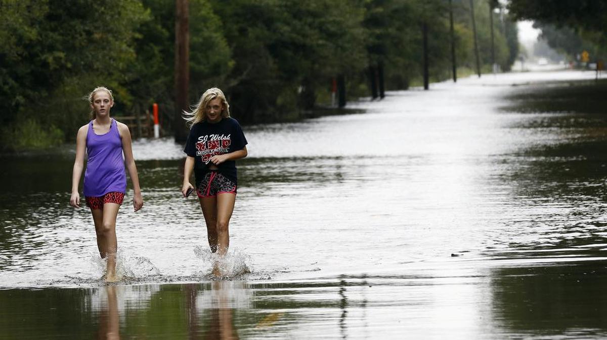 Serenity Vanderziel (izq.) y Shelbee LeJeune caminan por una calle inundada en la población de Iowa, Louisiana, el miércoles 30 de agosto de 2017.