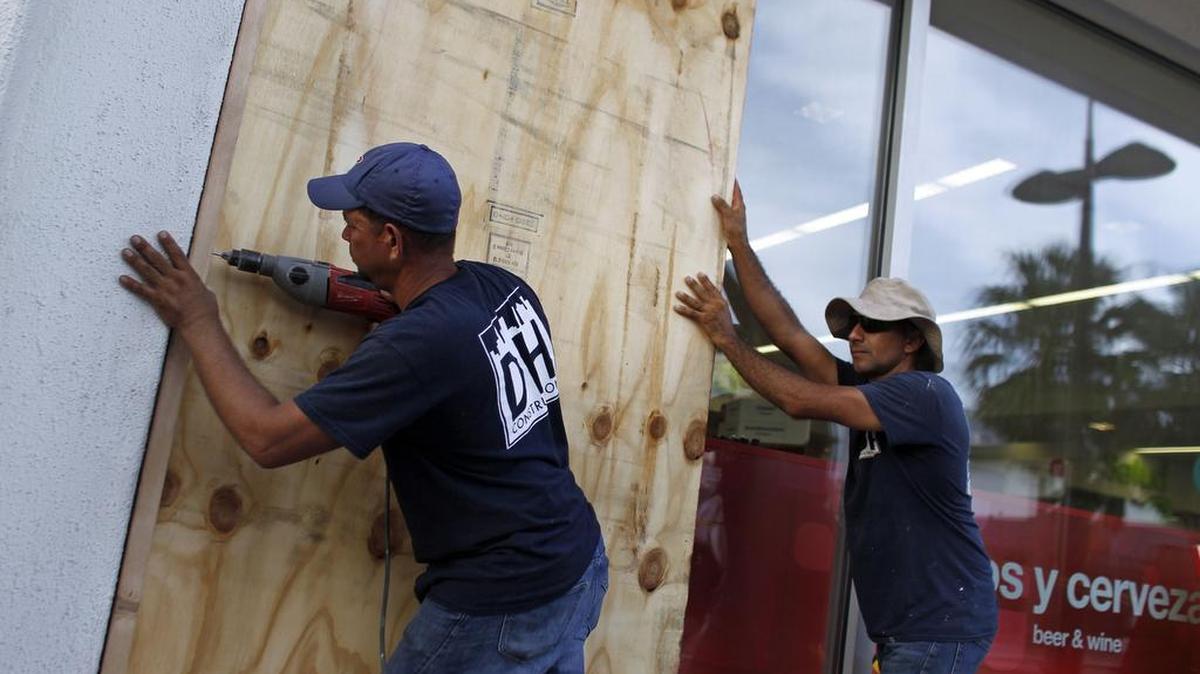 La gente protege las ventanas de un negocio en preparación para la llegada anticipada del huracán María en San Juan, Puerto Rico el 18 de septiembre de 2017.