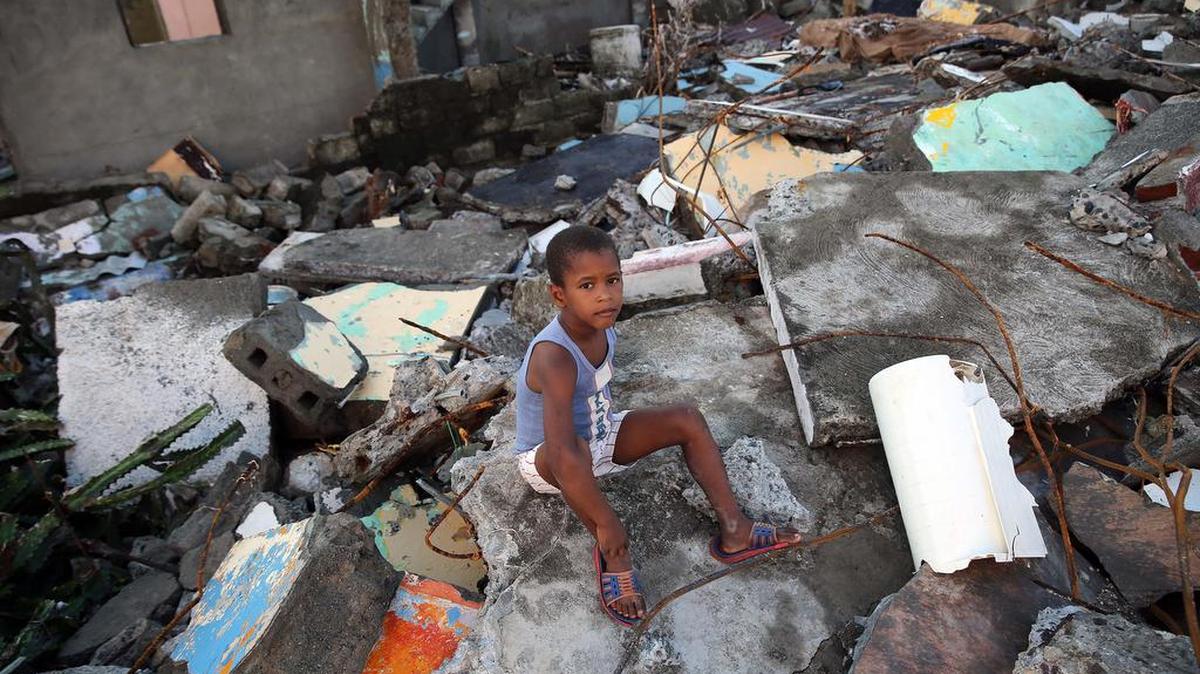 Un niño sentado en los escombros, el viernes 7 de octubre de 2016, tras el paso hace tres días del huracán Matthew en Baracoa (Cuba).