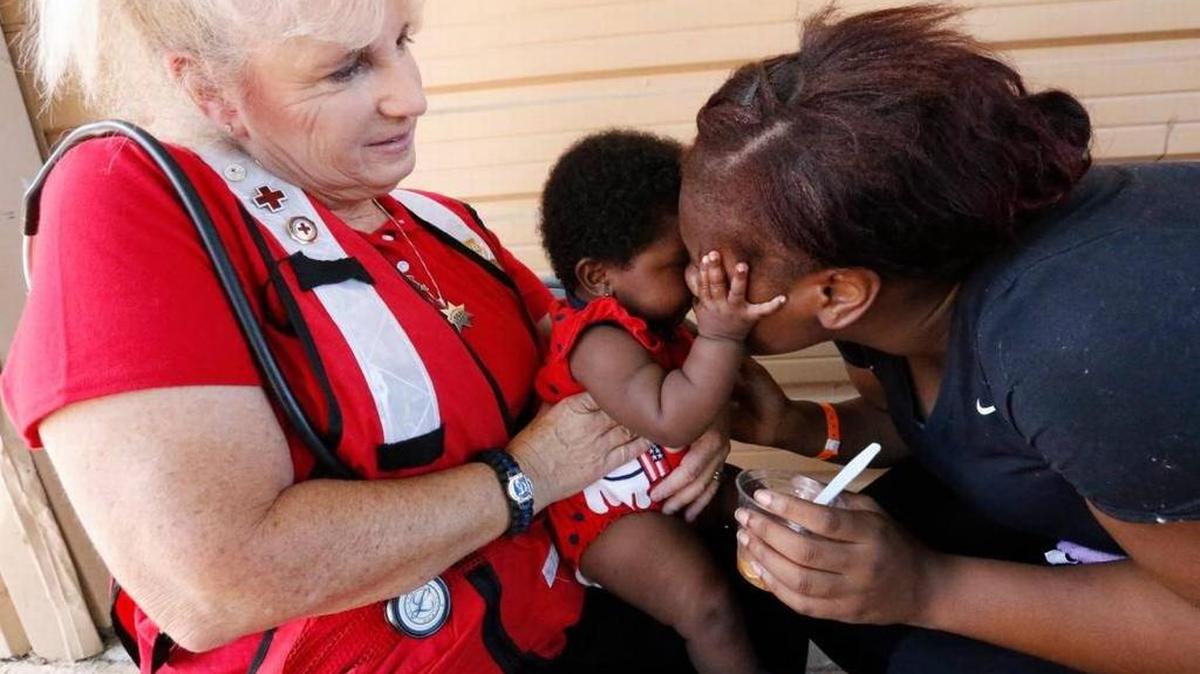 La enfermera de la Cruz Roja Liz Miller, de Placerville, California, asiste a Janay Washington, de 20 años y residente de North Miami Beach, a darle de comer a su hija de 5 meses, Ke'Lanni, en el Centro de Exposiciones de la Feria del Condado de Miami-Dade el martes, 19 de septiembre de 2017.