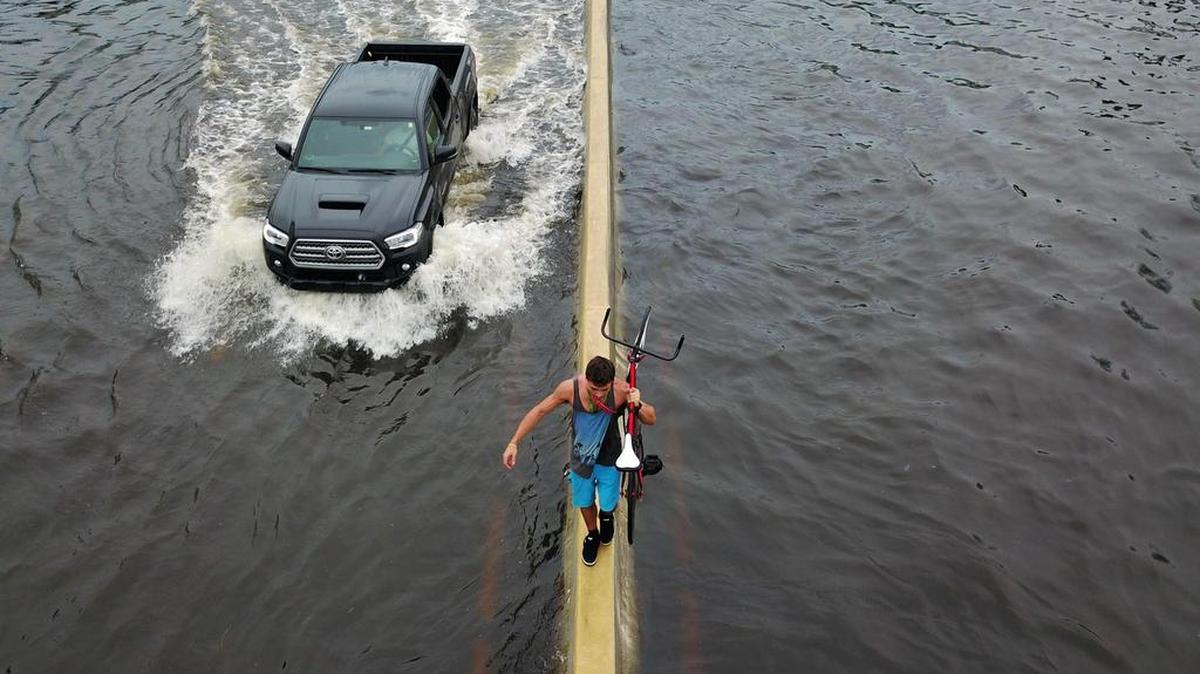 Un hombre camina en un divisor de la carretera mientras lleva su bicicleta tras el azote del huracán María en San Juan, Puerto Rico, el jueves 21 de septiembre de 2017.