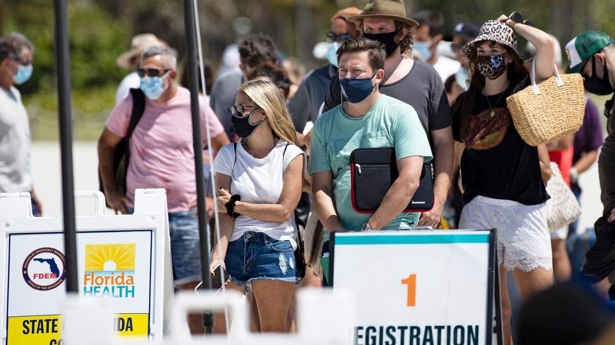 Decenas de personas hacen fila para recibir la vacuna de Johnson & Johnson contra el COVID-19, que requiere una sola dosis, en un punto de vacunación instalado en la playa a la altura de la calle 16 en Miami Beach, el domingo 2 de mayo de 2021.