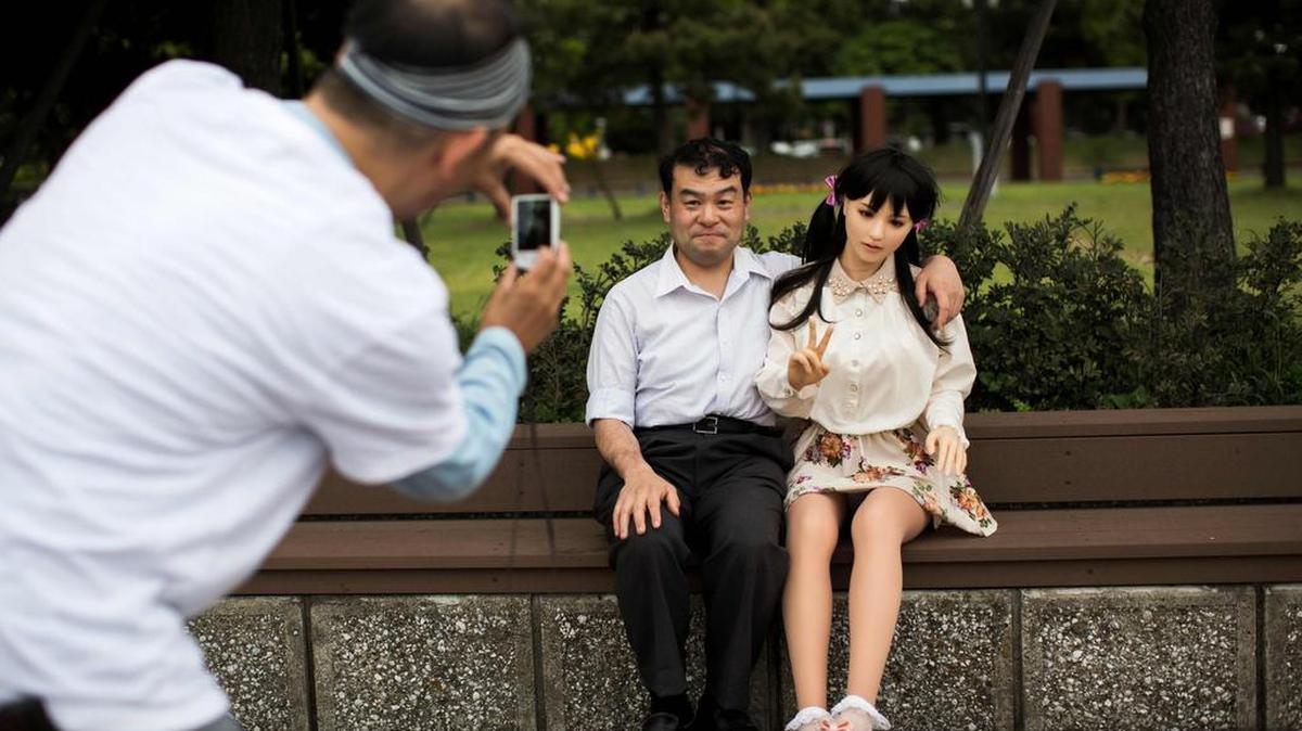 Un hombre toma fotos del fisioterapeuta Masayuki Ozaki y su muñeca de sexo en silicona Mayu en la bahía de Tokio.