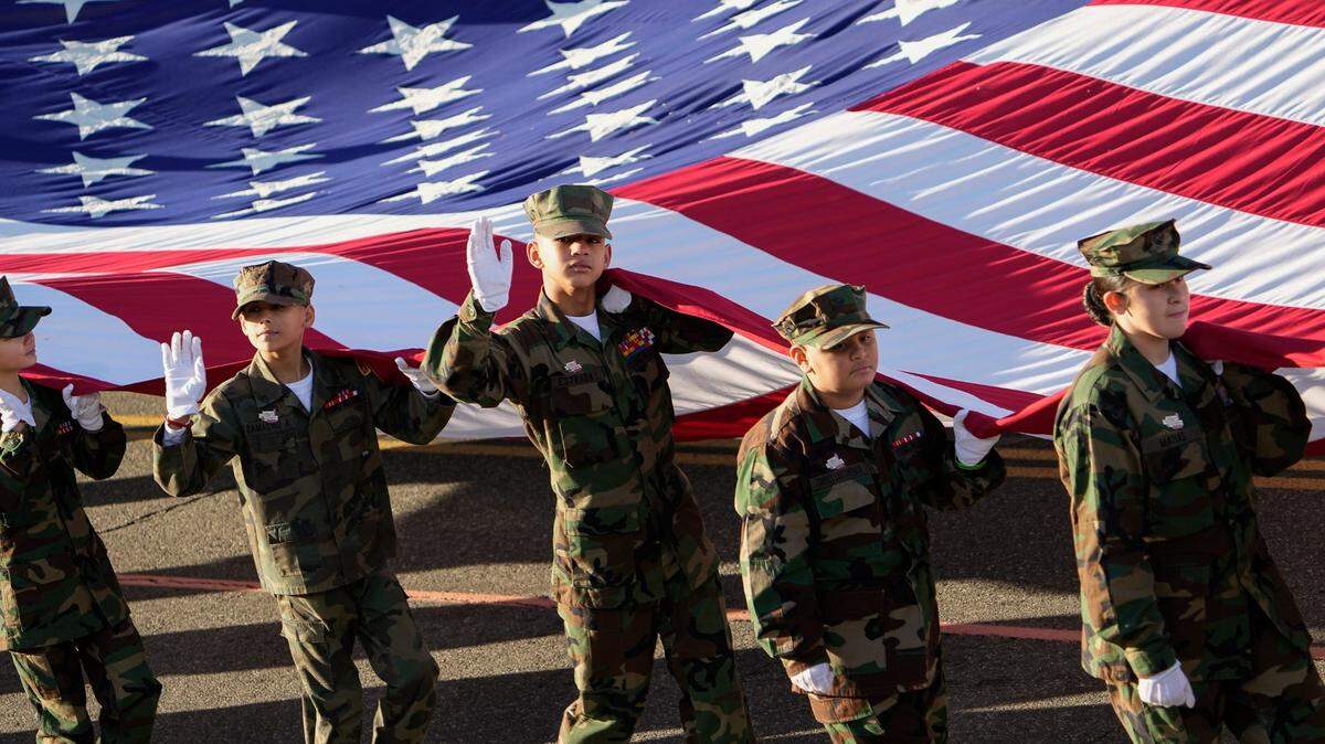 Niños llevan una bandera estadounidense junto a la Guardia de Color Montada del Cuerpo de Marines de Estados Unidos durante el Desfile del Torneo de las Rosas en Pasadena, California, el 1 de enero de 2022.