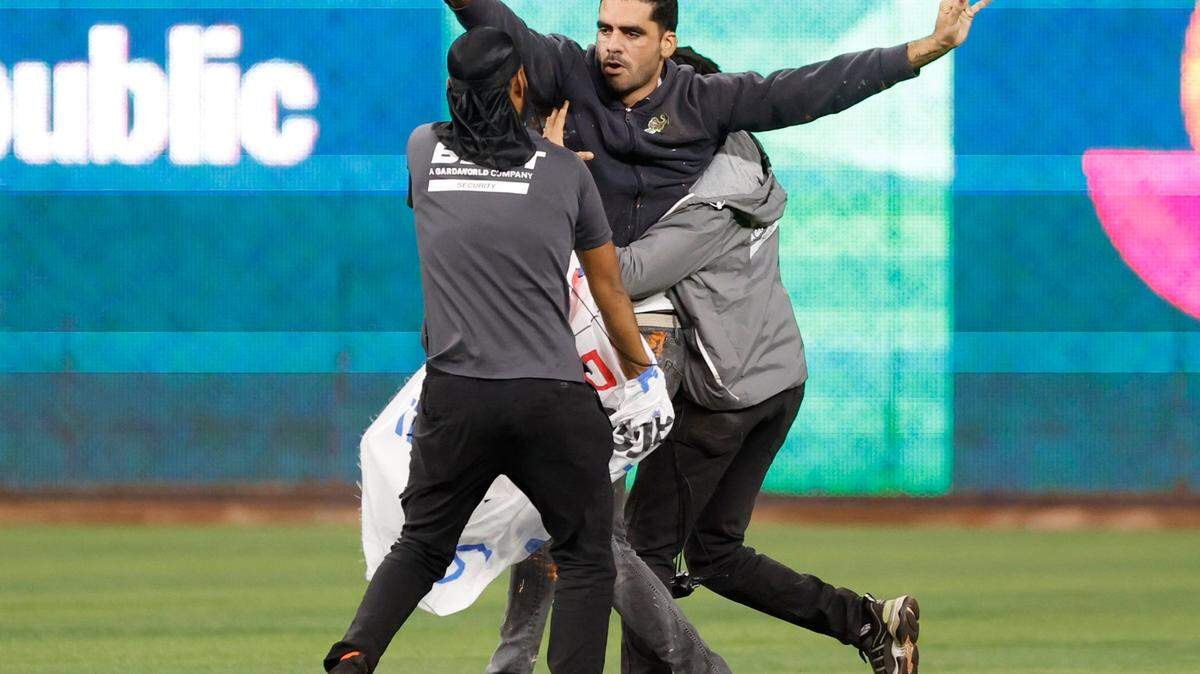Un manifestante es detenido por la seguridad del estadio después de correr por el campo durante el partido entre Estados Unidos y Cuba en la semifinal del Clásico Mundial de Béisbol en el LoanDepot Park en Miami, Florida, el domingo 19 de marzo de 2023.