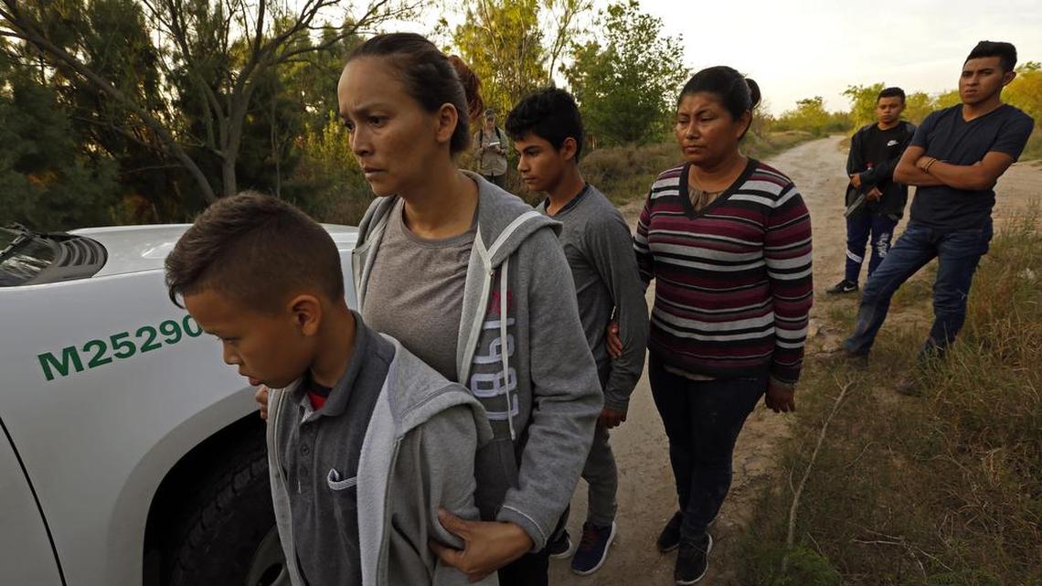 Inmigrantes que cruzaron recientemente la frontera con México cerca de la ciudad tejana de McAllen esperan a ser transportados a un centro de detención.