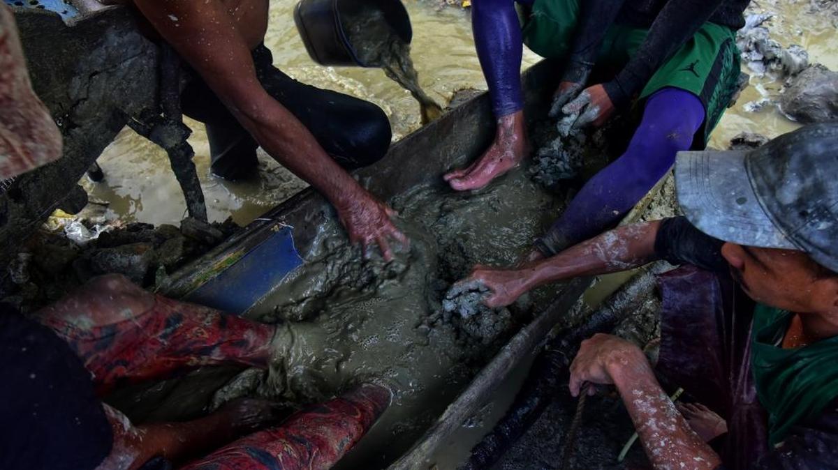 Un grupo de mineros busca oro disolviendo el fango con los pies en, Paracale, Filipinas, el 22 de marzo. Estos trabajadores enfrentan duras condiciones, pasan hasta cuatro horas nadando cubiertos por el mango buscando pequeñas piedras que contengan oro.