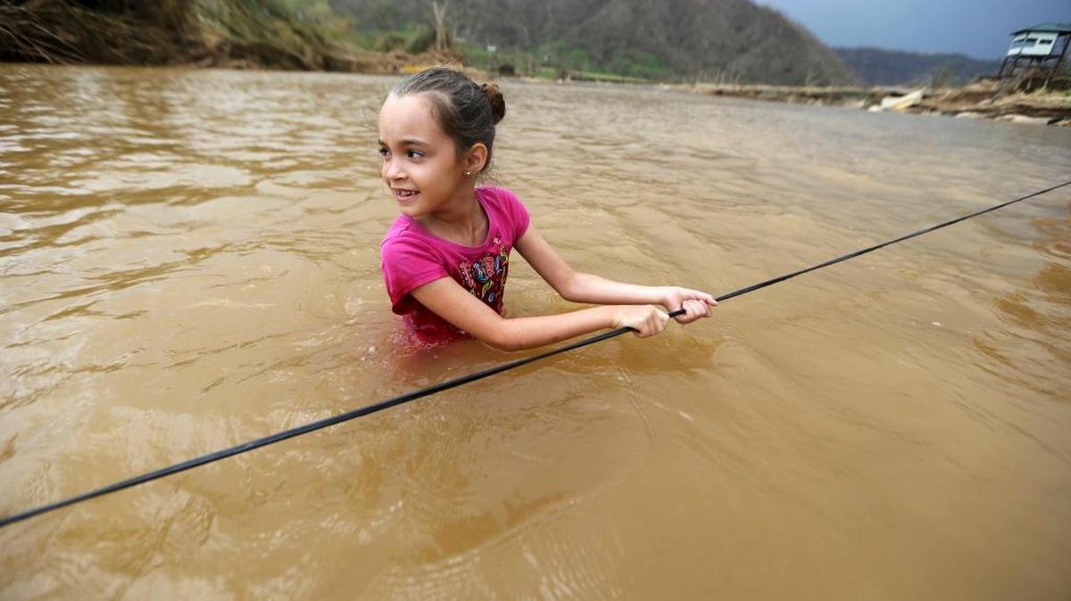 Ruby Rodríguez, de 8 años de edad, cruza un río con su familia en Morovis, Puerto Rico, después que el huracán María derribó un puente.