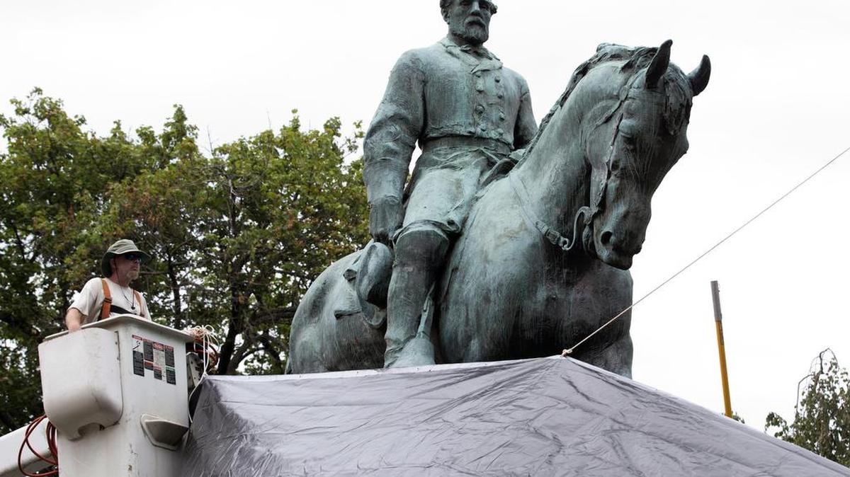 Empleados municipales cubren con lona alquitranada la estatua del general confederado Robert E. Lee en el Parque de la Emancipación en Charlottesville, Virginia. Archivo.