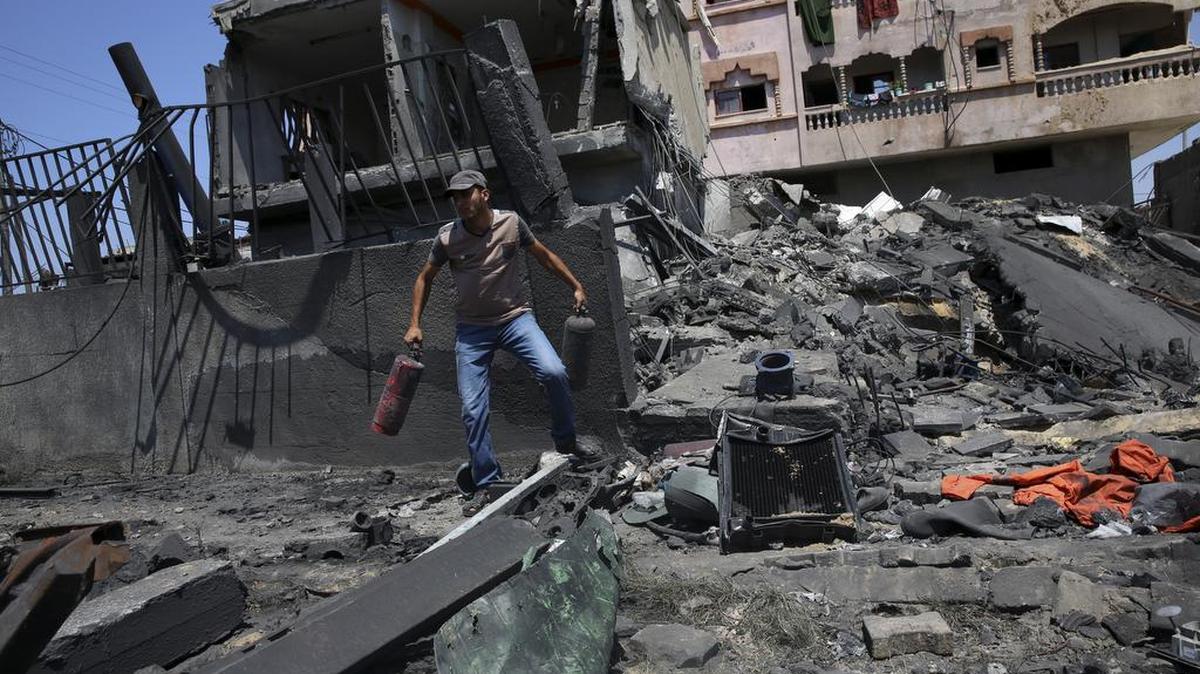 Un palestino rescata objetos de los escombros de un centro de distribución de agua en la Franja de Gaza, destruido en un ataque de la aviación israelí el pasado jueves.