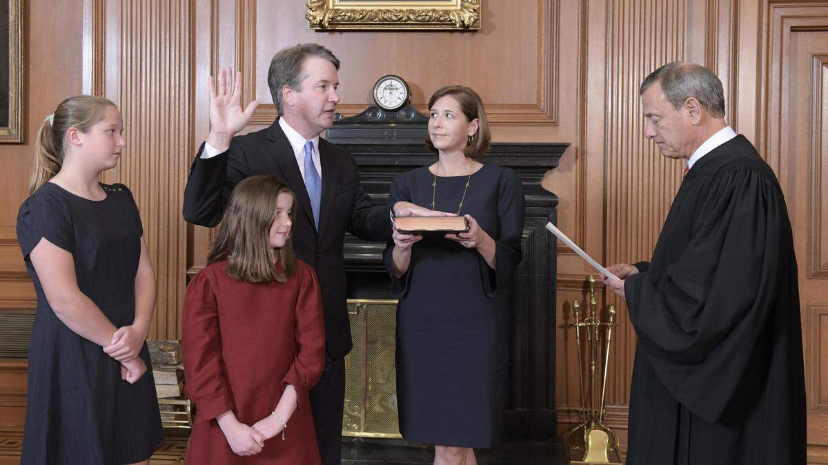 El juez  Brett Kavanaugh, acompañado de su esposa e hijas, presta juramento como nuevo juez de la Corte Suprema de Justicia de EEUU, ante el presidente de la Corte, el juez John Roberts, el sábado en Washington.