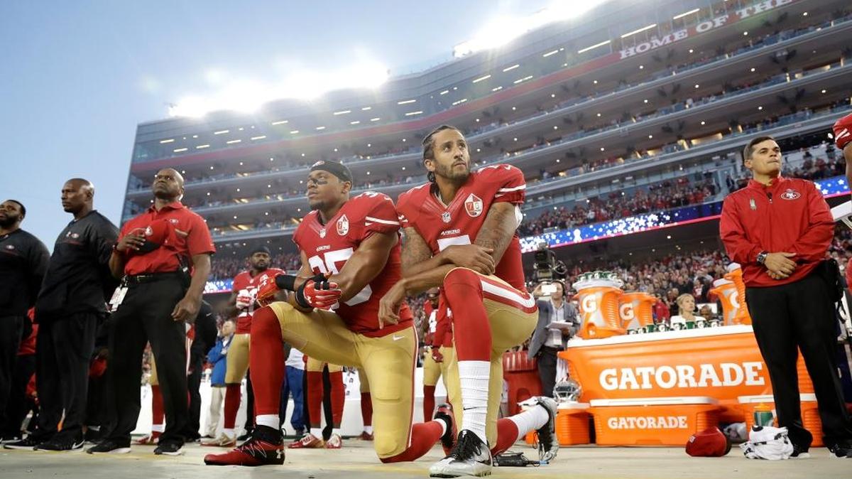 Los jugadores de los San Francisco 49ers Eric Reid (izq.) y Colin Kaepernick (7) se arrodillan al tocar el himno nacional antes de un partido de la NFL en Santa Clara, California, el 12 de septiembre, en una protesta contra el racismo.