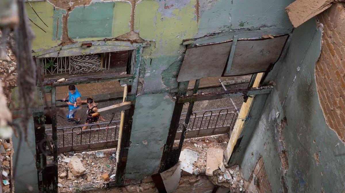 Dos personas caminan frente a un edificio que colapsó por las lluvias, en noviembre de 2013 en La Habana.