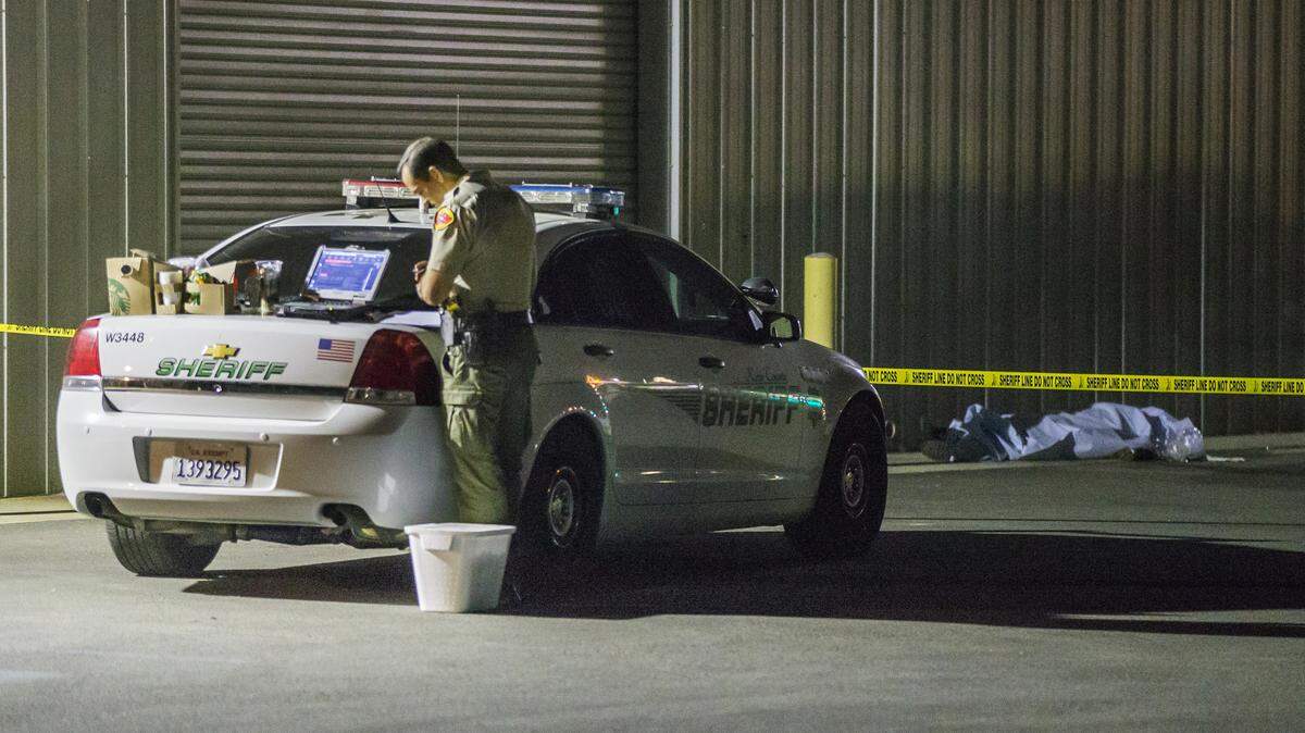 Un agente policial del condado Kern vigila el área donde ocurrió un tiroteo, el miércoles en Bakersfield, California. Una de las víctimas está en el fondo. Un hombre mató a cinco personas, incluyendo a su esposa, y después se suicidó.