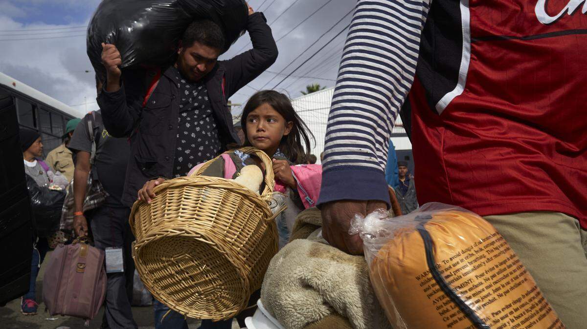 Brittany Ríos, de Honduras (centro), lleva una cesta con sus peluches durante el traslado de su familia y otros inmigrantes desde un refugio a un edificio más grande, el viernes en Tijuana, México.