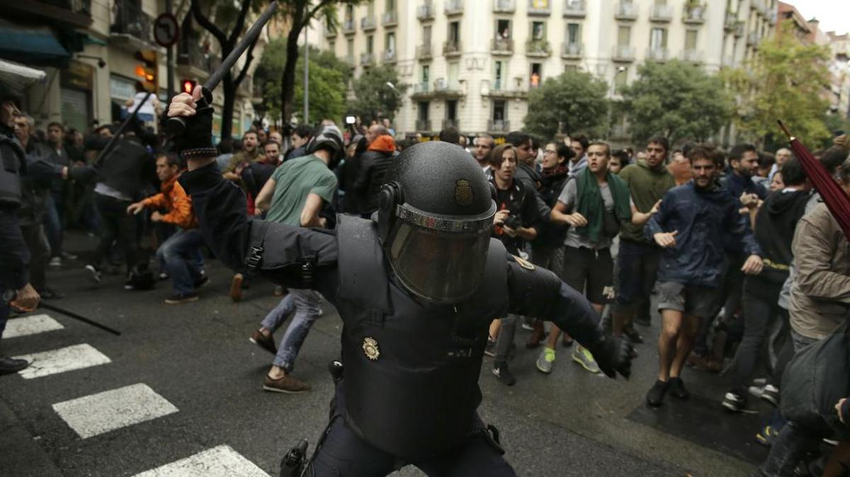 Policías antimotines blanden sus porras contra personas que acudieron al referendo en Barcelona, el domingo pasado.