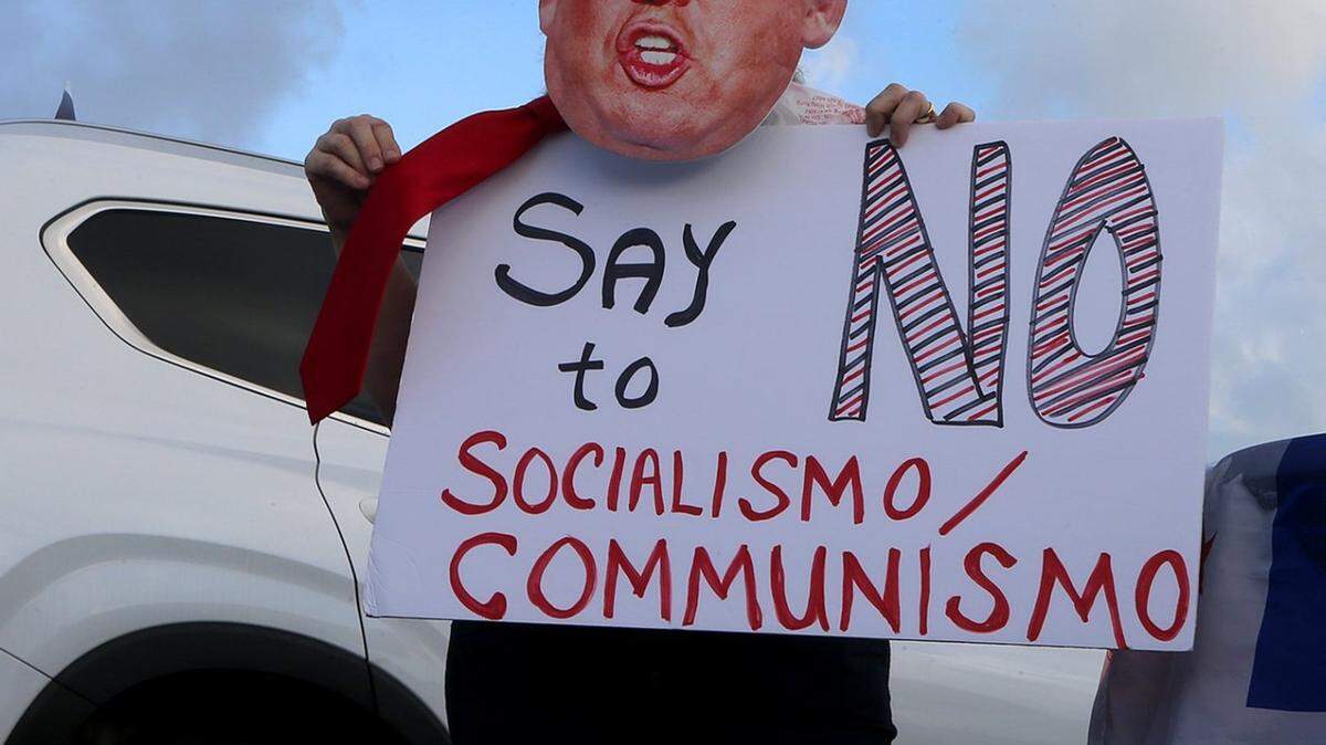 La campaña presidencial del presidente Donald Trump ha organizado caravanas anticomunistas para motivar a sus seguidores. En la foto, una mujer sostiene un cartel durante un evento el sábado 10 de octubre de 2020 en Miami, Florida.