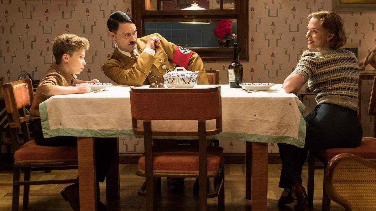 Los actores Roman Griffin Davis (izq.), Taika Waititi y Scarlet Johansson, en una escena de la película “JoJo Rabbit”. Waititi escribió y dirigió el filme. 
