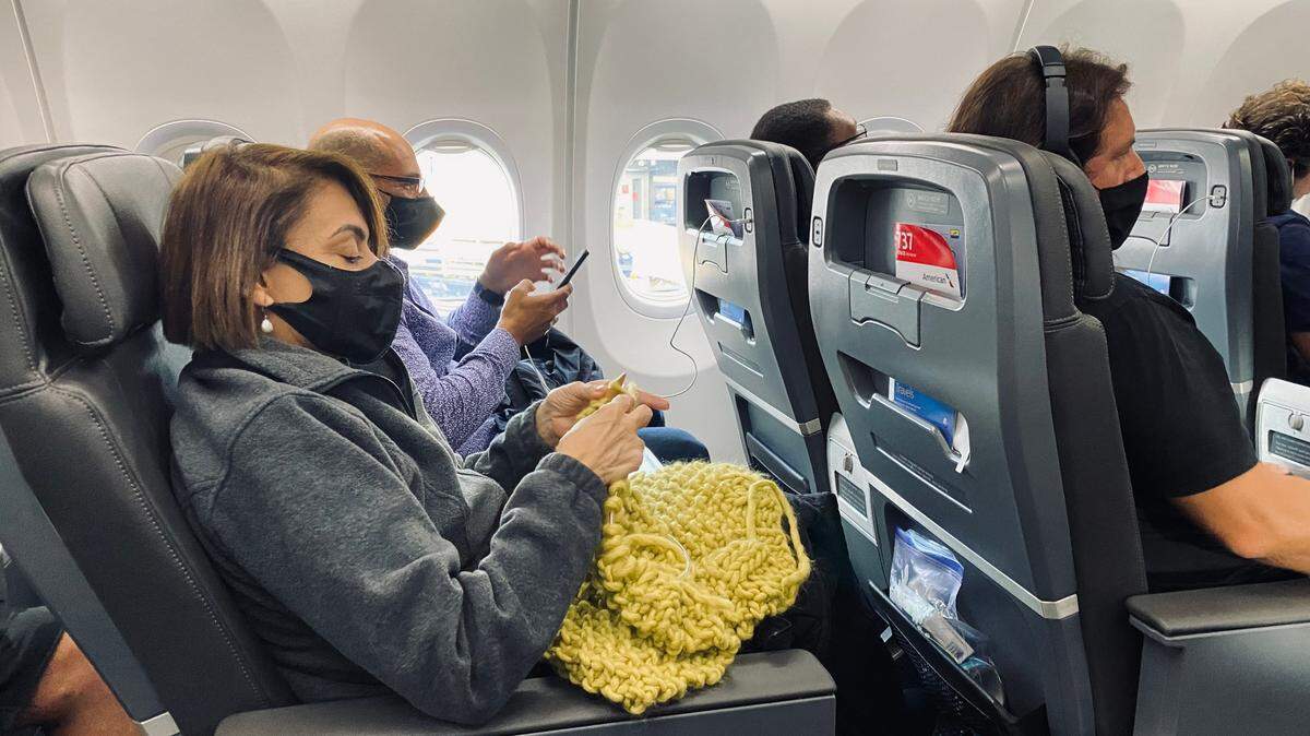 La periodista María Antonieta Collins tejiendo una colcha durante un viaje por avión.