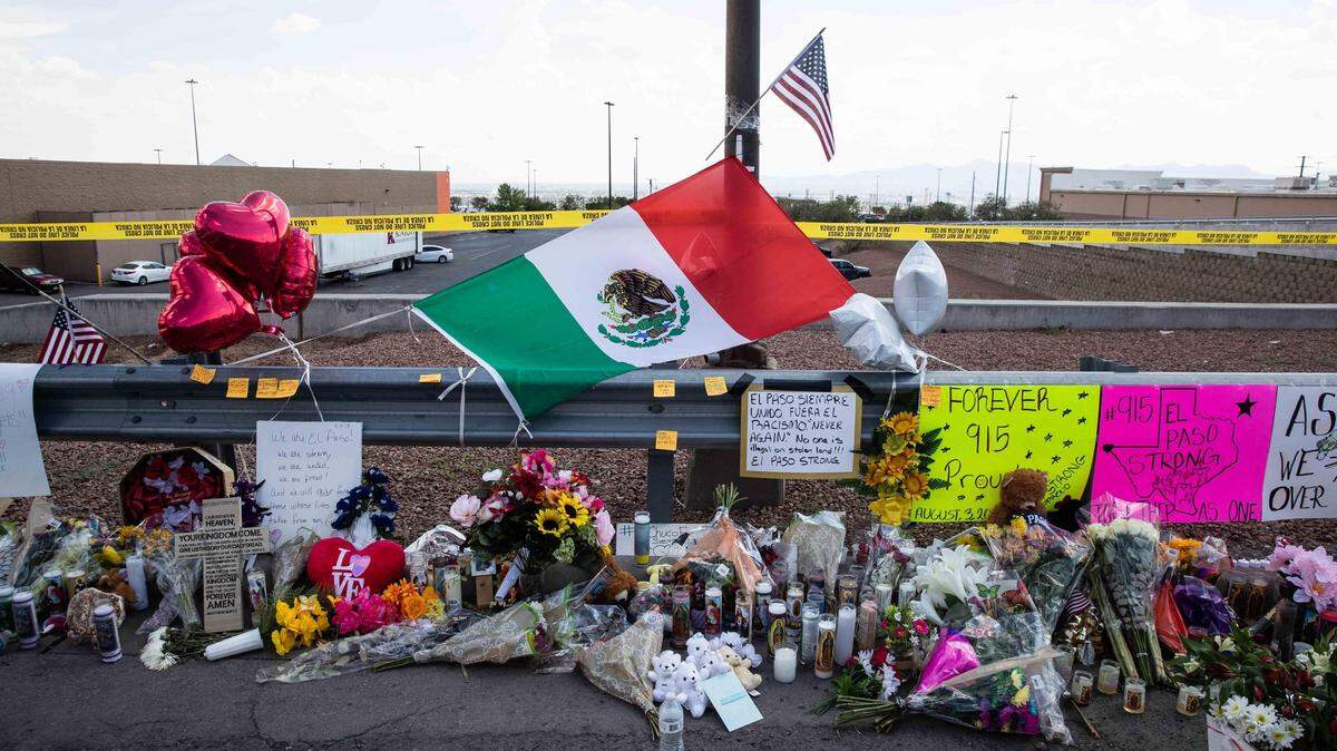 Una bandera de México destaca entre las flores, velas, fotos y peluches que fueron dejados en homenaje a las víctimas de la matanza en El Paso, Texas, frente a la tienda Walmart en donde ocurrió la tragedia.