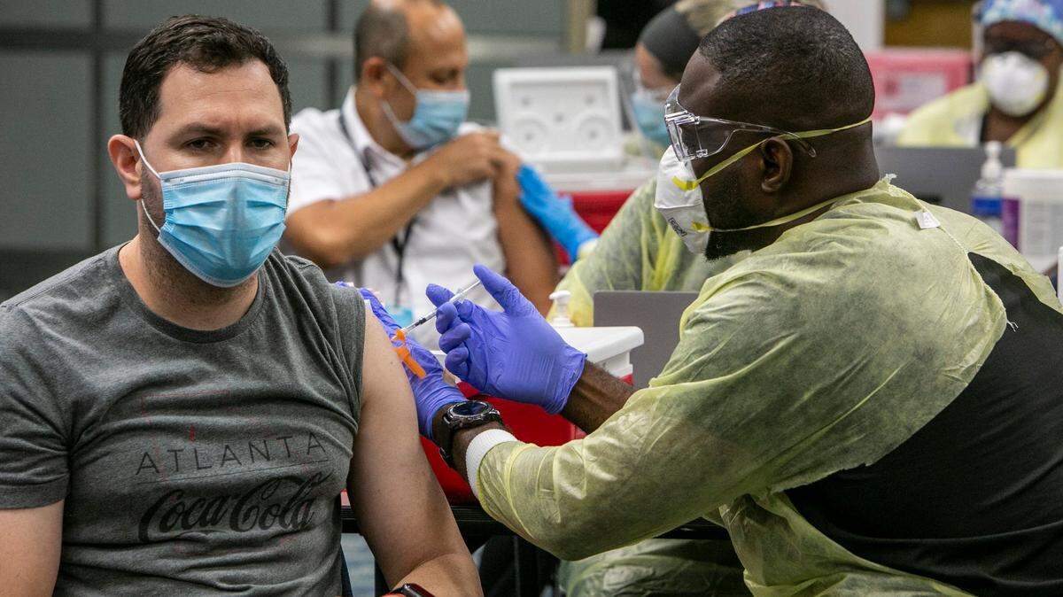Lázaro Navarro (izq.), un empleado de American Airlines, recibe una dosis de la vacuna Pfizer contra el coronavirus, el 9 de mayo de 2021, en el Aeropuerto Internacional de Miami.