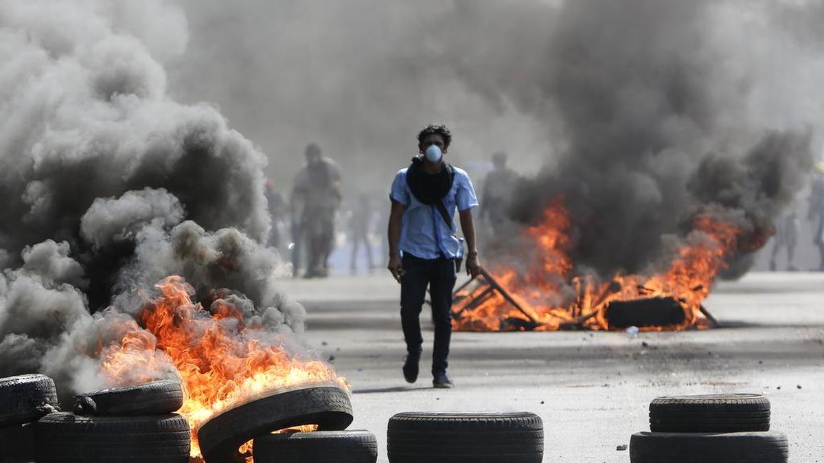 Un manifestante enmascarado camina entre neumáticos quemados en Managua, durante las protestas de fines de abril contra el gobierno de Daniel Ortega.