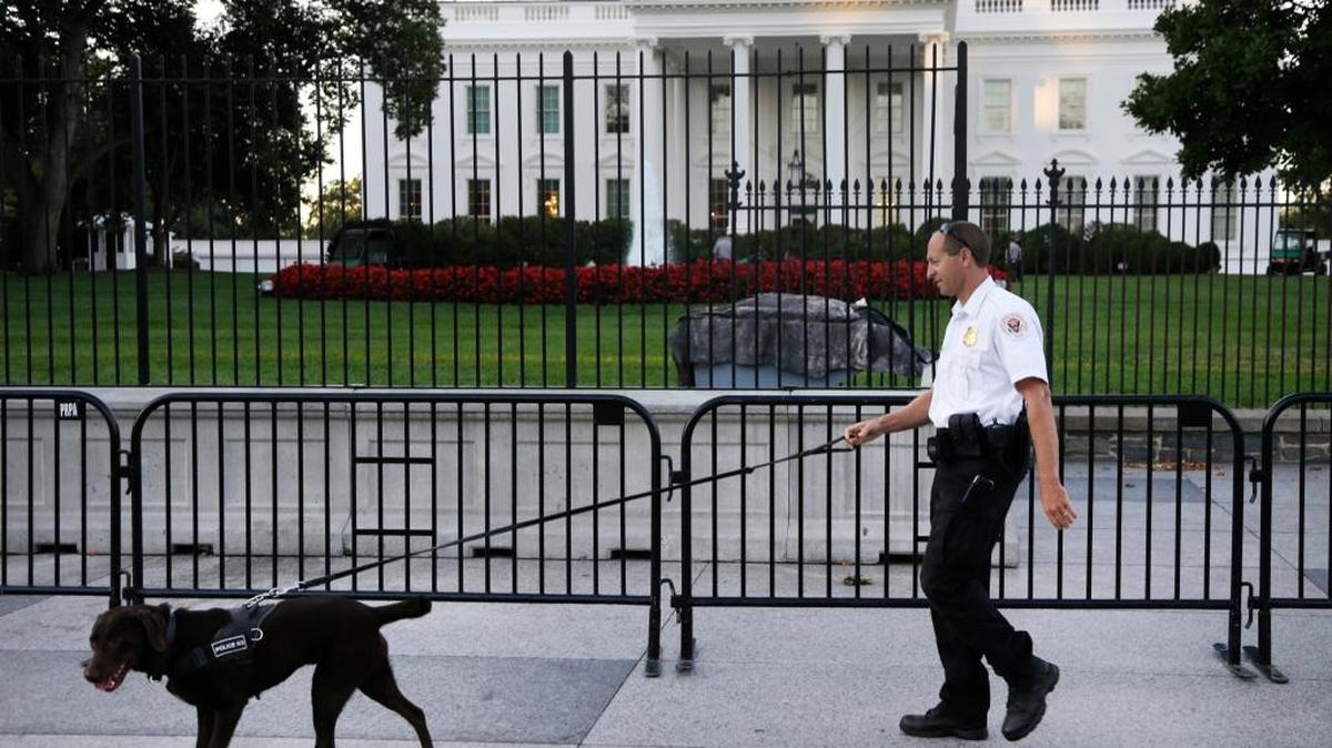 Un miembro del Servicio Secreto camina con un perro de la brigada K-9 alrededor de Pennsylvania Avenue frente a la Casa Blanca, en Washington.