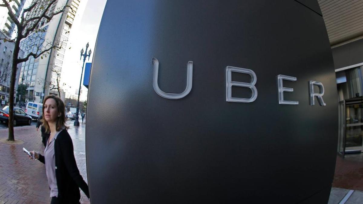 Una mujer pasa frente al logo de la compañía de servicios de autos Uber, en San Francisco.