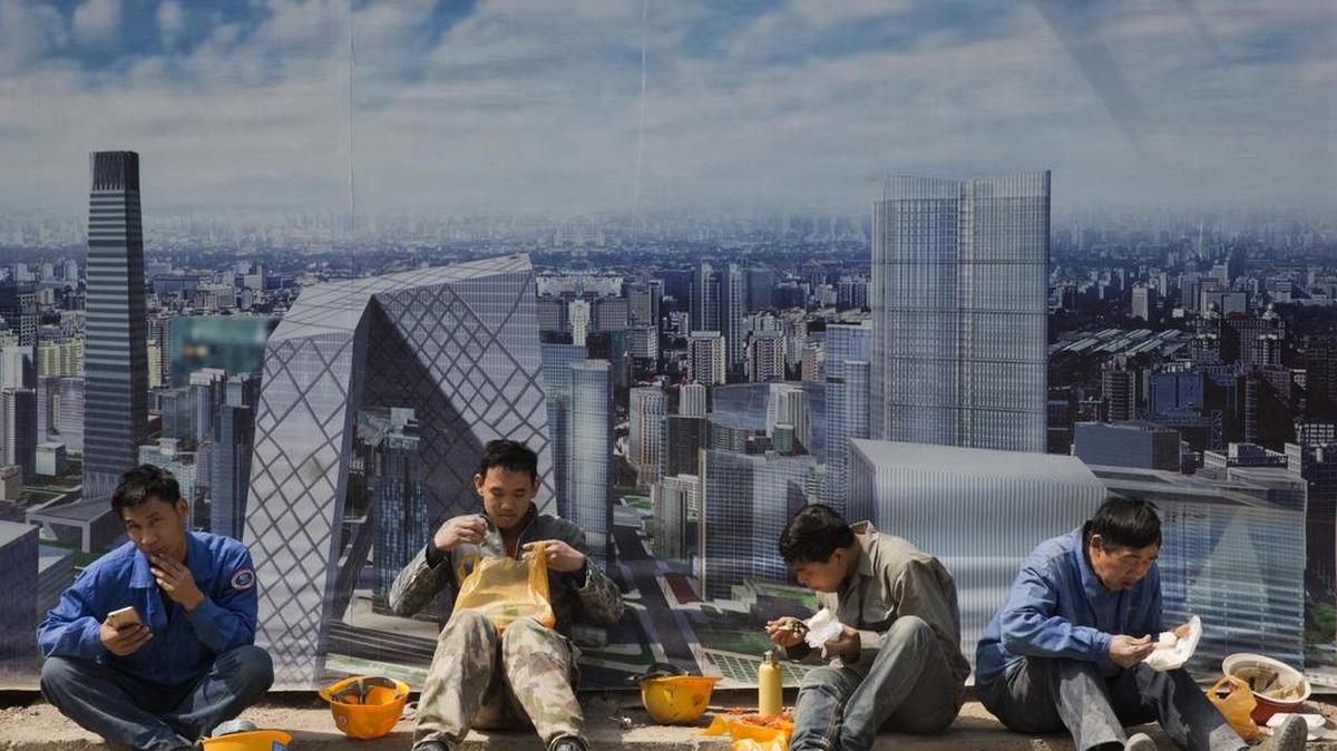Obreros de la construcción toman un receso para almorzar junto a un mural en Pekín. Las economías en desarrollo de Asia disfrutan de un crecimiento sostenido.