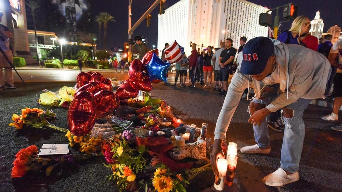 Un hombre coloca una vela en un tributo improvisado cerca del hotel Mandalay, en Las Vegas, a las víctimas del ataque cometido por un hombre, Stephen Paddock, que abrió fuego contra los asistentes a un concierto de música country.