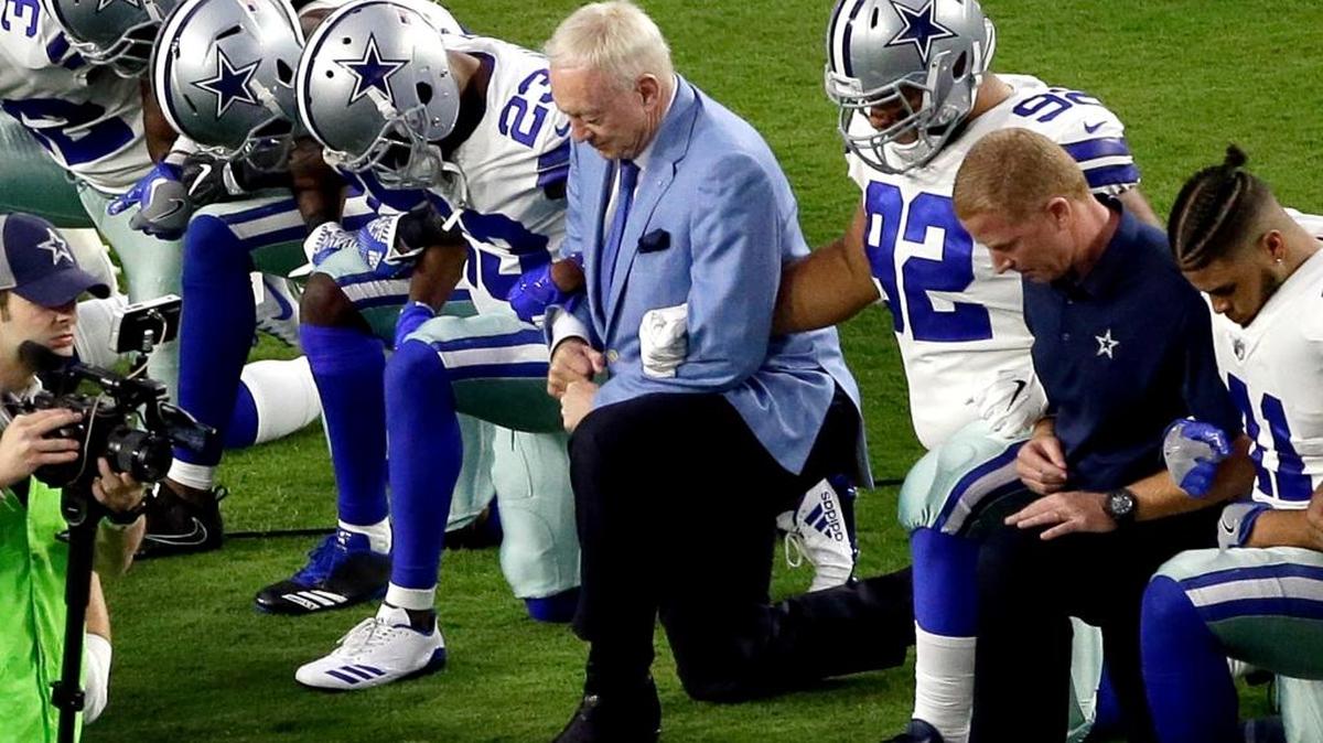 Los Dallas Cowboys, con el dueño del equipo, Jerry Jones, al centro, se hincan de rodillas antes de la interpretación del himno nacional en un partido contra los Arizona Cardinals en Glendale, Arizona, el 25 de septiembre.
