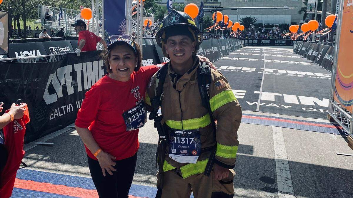 La periodista María Antonieta Collins con Claudio Navas, bombero de Miami Beach, el domingo 6 de febrero de 2022. Navas lleva varios anos participando en el medio maratón de Miami usando el traje y equipo de bombero en honor a su amigo Danny Álvarez, quien falleció tras suicidarse. Navas se enfoca en crear conciencia sobre los devastadores efectos de la depresión.